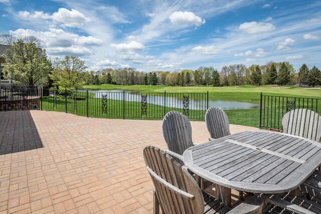 view of patio with a water view, outdoor dining area, and view of wooded area