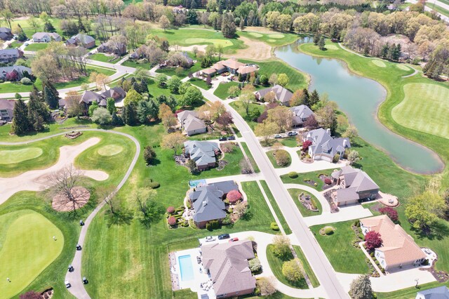 view of property location featuring a nearby body of water, nearby suburban area, and a golf course