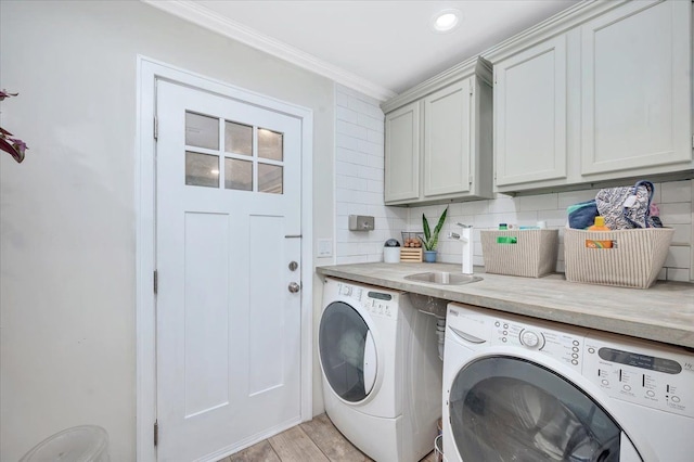 washroom with a sink, cabinet space, ornamental molding, light wood-type flooring, and separate washer and dryer