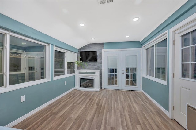 unfurnished living room featuring vaulted ceiling, baseboards, french doors, and wood finished floors