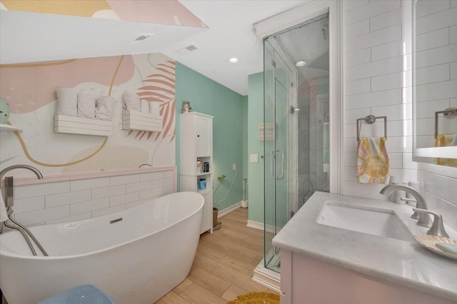 full bath with wood finished floors, baseboards, a shower stall, a freestanding tub, and vanity