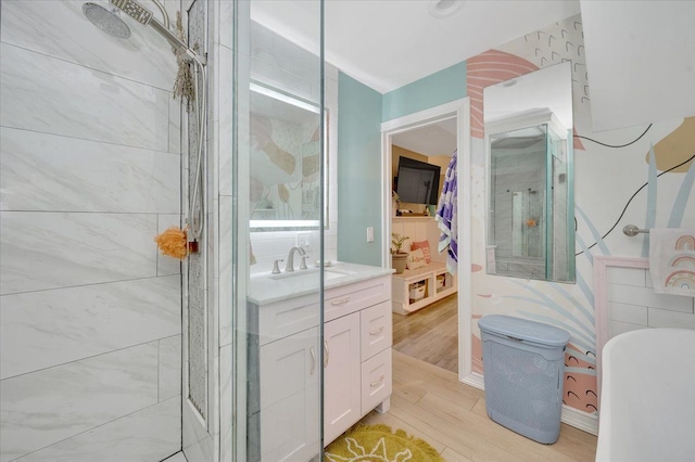 full bathroom with a stall shower, vanity, a freestanding tub, and wood finished floors