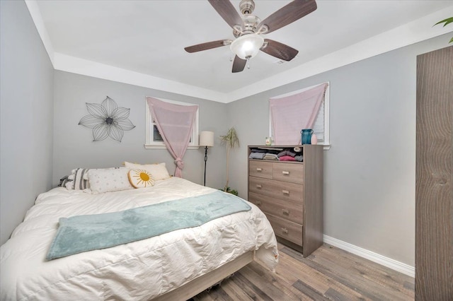 bedroom with light wood-style flooring, baseboards, and ceiling fan