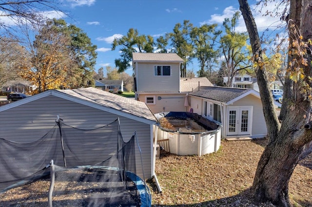 rear view of house with an outbuilding, french doors, and a covered pool
