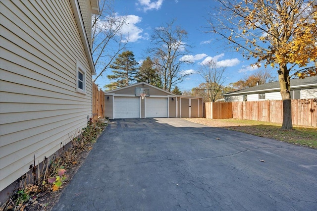 view of property exterior with an outdoor structure, fence, and a detached garage