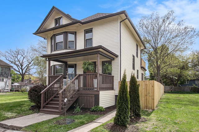 view of front of home with a porch, a front lawn, and fence