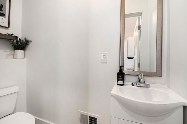half bath with toilet, visible vents, and vanity