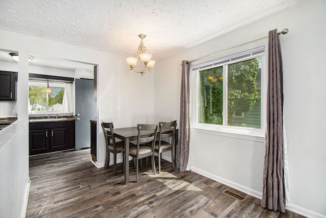 dining space featuring a chandelier, dark wood-style floors, healthy amount of natural light, a textured ceiling, and baseboards