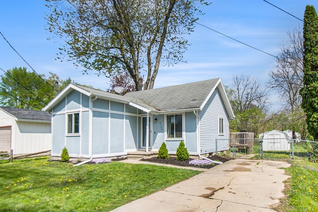 view of front of property featuring an outdoor structure, a gate, a shingled roof, and concrete driveway
