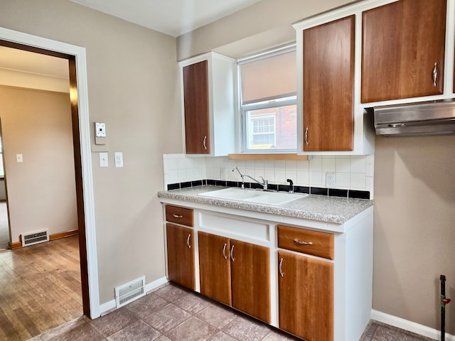 kitchen with a sink, tasteful backsplash, and visible vents