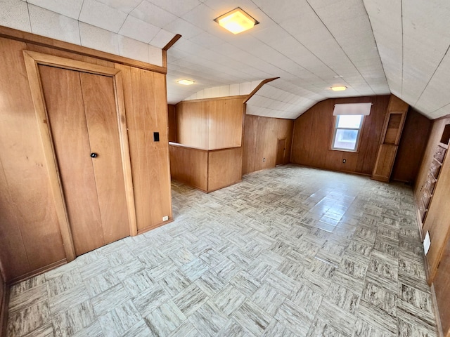 bonus room with vaulted ceiling and wood walls