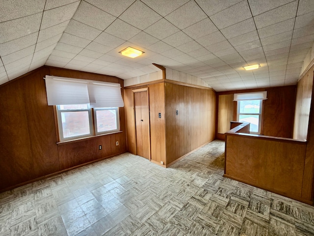 additional living space featuring elevator, wood walls, baseboards, and lofted ceiling