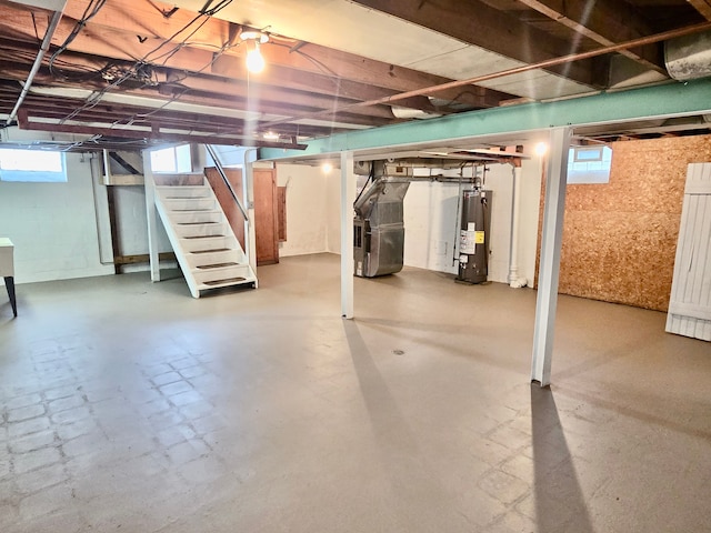 basement with stairs, a healthy amount of sunlight, heating unit, and electric water heater