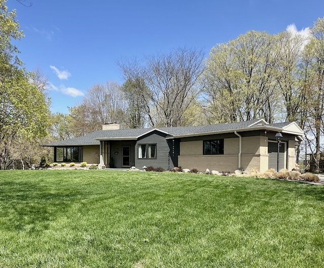 view of front of property with brick siding, a chimney, and a front yard