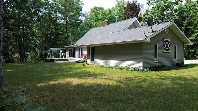 200 S Shearer Rd, Gladwin, MI 48624 - view of side of home with a yard, roof with shingles, a chimney, and a wooden deck