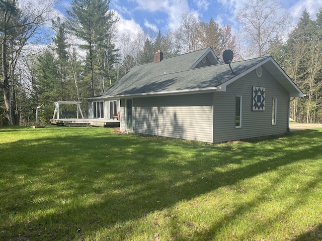 200 S Shearer Rd, Gladwin, MI 48624 - view of side of property featuring a yard, a wooden deck, and a chimney