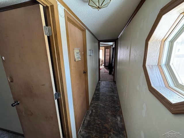 corridor with stone finish floor, a wealth of natural light, and a textured ceiling