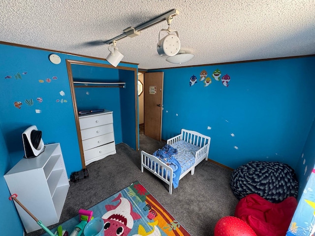 carpeted bedroom featuring a textured ceiling, rail lighting, and a closet