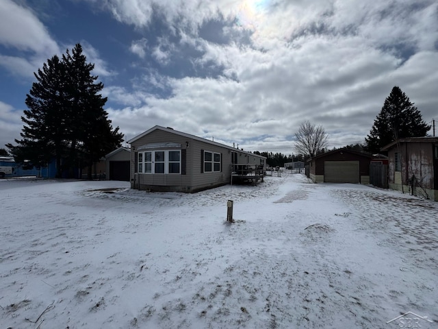 view of snow covered exterior with an outbuilding and a garage