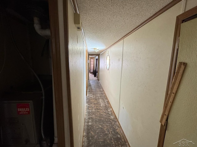 hallway featuring a textured ceiling and a textured wall
