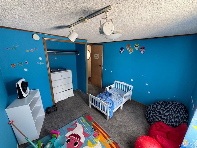 bedroom with a textured ceiling, carpet flooring, a closet, and track lighting