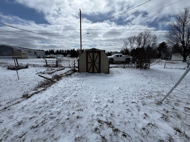 snowy yard featuring an outbuilding, fence, and a storage unit