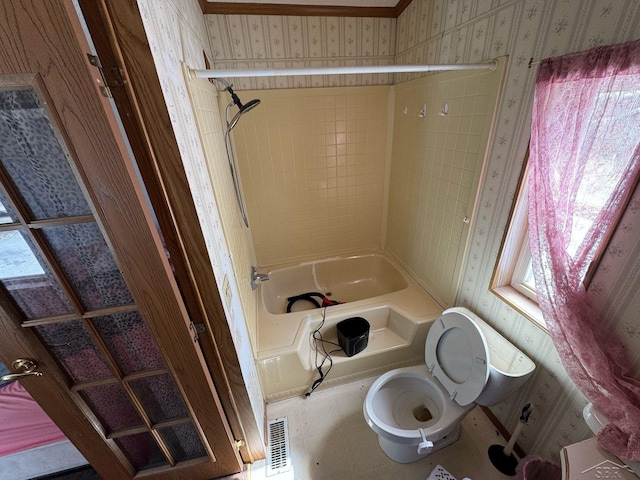 full bathroom featuring toilet, shower / washtub combination, wallpapered walls, and visible vents