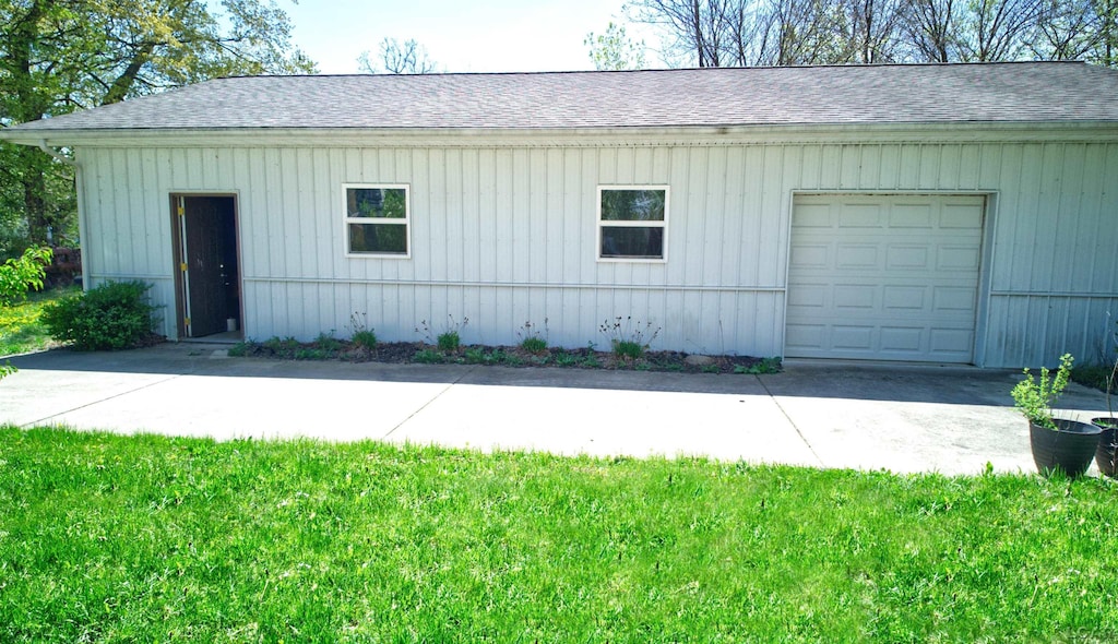 exterior space with concrete driveway and roof with shingles