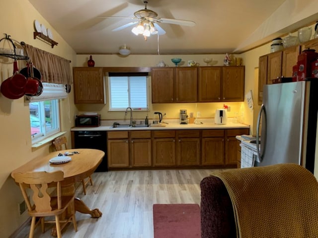 kitchen with light wood finished floors, brown cabinets, a sink, freestanding refrigerator, and black dishwasher