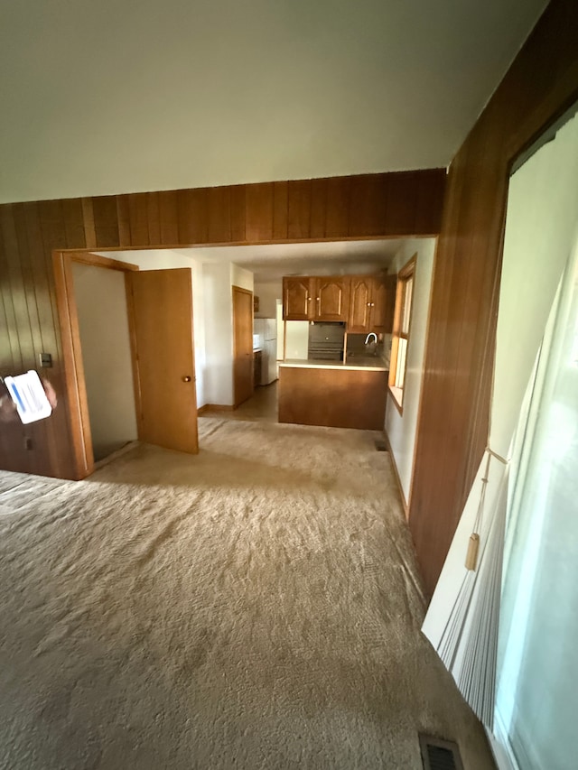 unfurnished living room featuring light carpet, wood walls, and visible vents