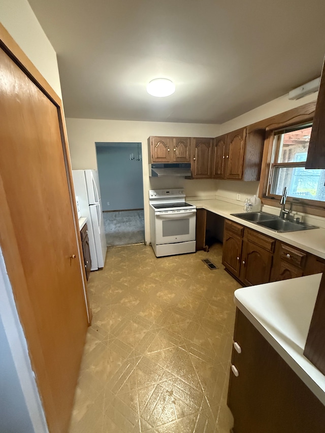 kitchen featuring a sink, white appliances, light floors, under cabinet range hood, and light countertops