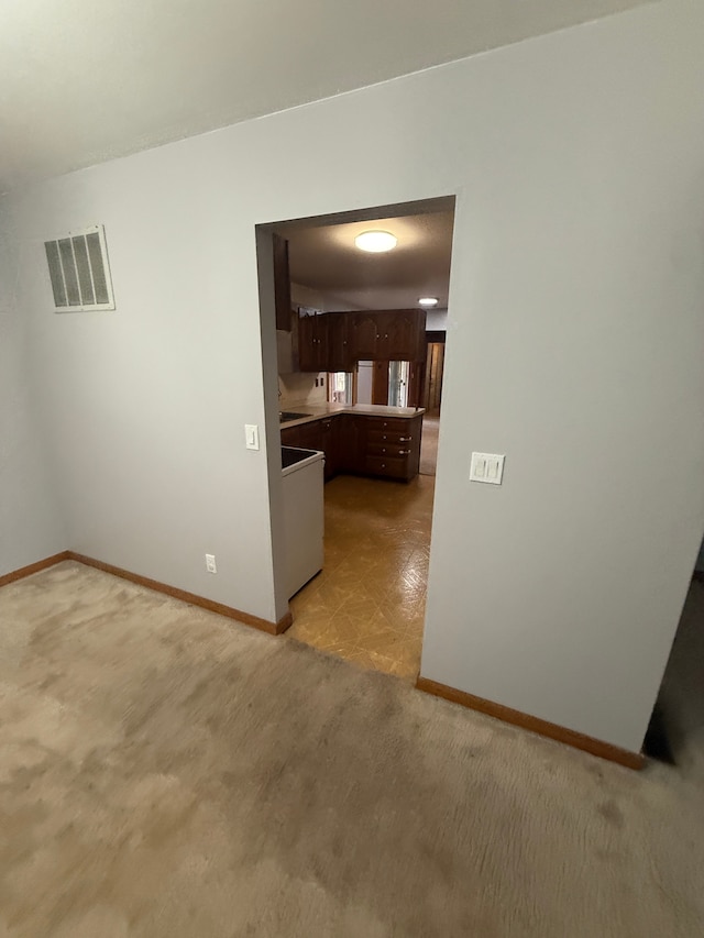 spare room featuring light carpet, baseboards, and visible vents
