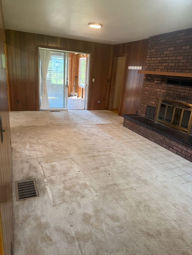 unfurnished living room featuring wood walls, a fireplace, visible vents, and carpet floors