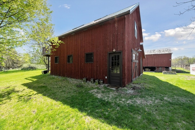view of home's exterior featuring a lawn, a pole building, and an outbuilding