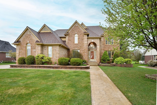 traditional home featuring a front yard, brick siding, and a shingled roof