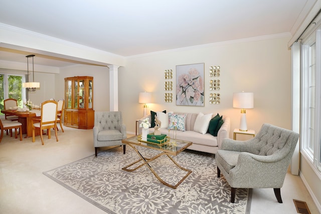 carpeted living room featuring a healthy amount of sunlight, visible vents, ornate columns, and ornamental molding