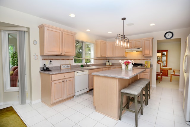 kitchen with light countertops, light brown cabinetry, under cabinet range hood, and dishwasher