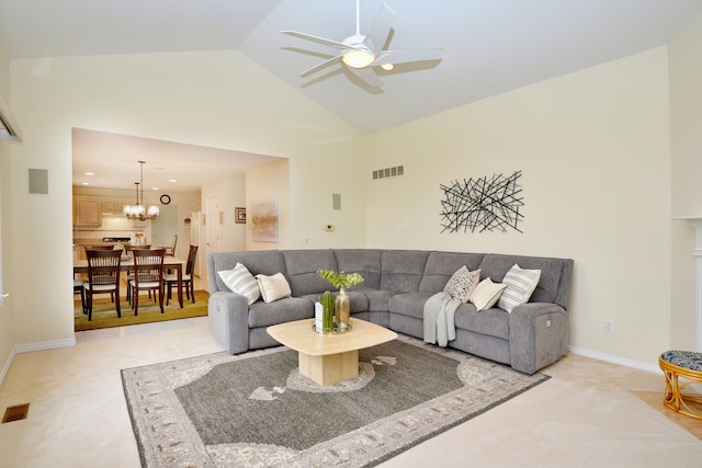 living area with ceiling fan with notable chandelier, high vaulted ceiling, visible vents, light carpet, and baseboards