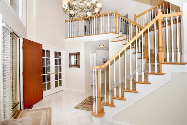 foyer with a notable chandelier, baseboards, stairs, tile patterned floors, and a high ceiling