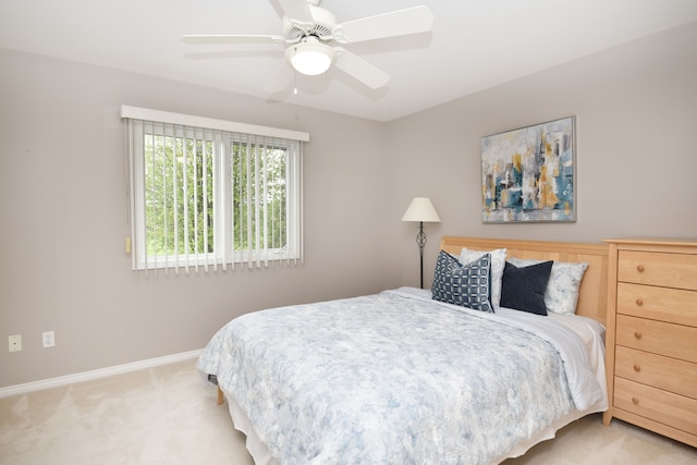 bedroom featuring light colored carpet, baseboards, and a ceiling fan