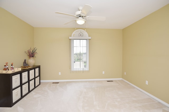 unfurnished room featuring light colored carpet, visible vents, baseboards, and a ceiling fan
