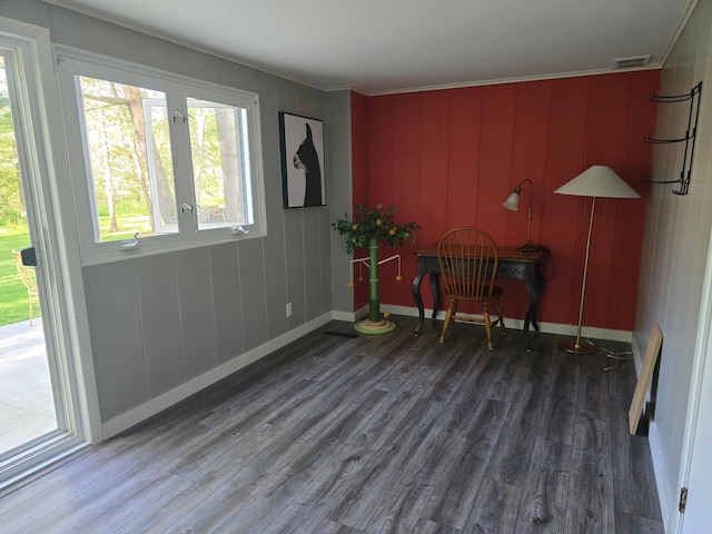 living area with wood finished floors, ornamental molding, and baseboards