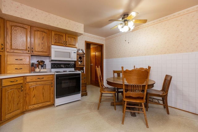 70765 Carter Ave, Niles, MI 49120 - kitchen with wallpapered walls, brown cabinetry, electric range, wainscoting, and white microwave