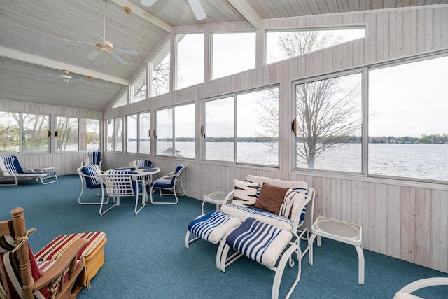 sunroom / solarium with beam ceiling, a water view, a ceiling fan, and a healthy amount of sunlight