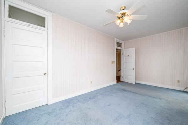 spare room with ornamental molding, carpet floors, a ceiling fan, and baseboards