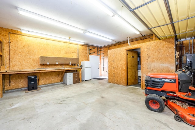 garage featuring freestanding refrigerator and a workshop area