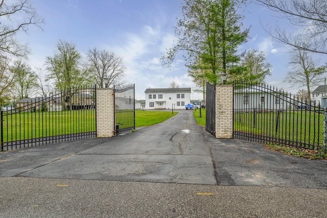 view of gate with fence and a lawn