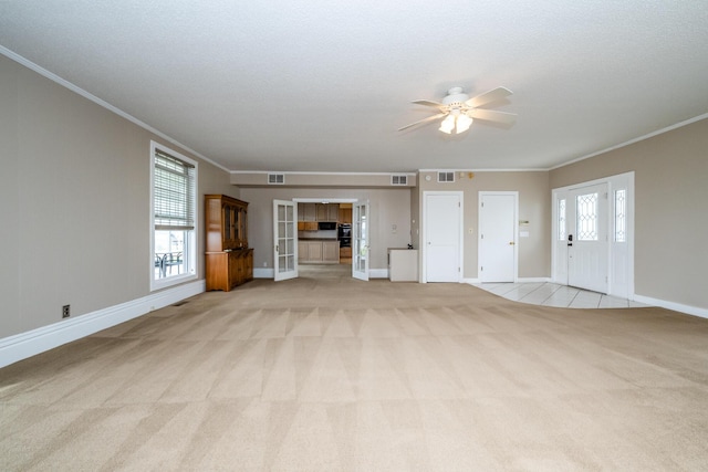 unfurnished living room with a ceiling fan, crown molding, visible vents, baseboards, and light colored carpet