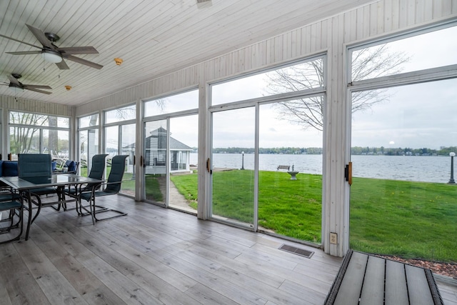sunroom with ceiling fan, a water view, outdoor dining space, and visible vents
