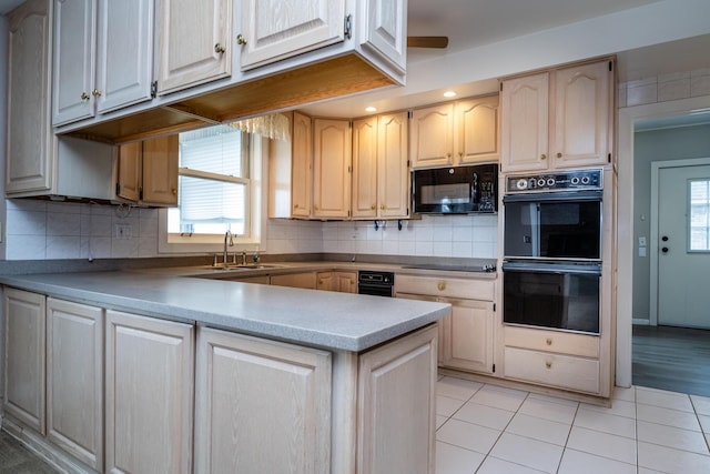 kitchen featuring black appliances, a peninsula, a sink, and plenty of natural light